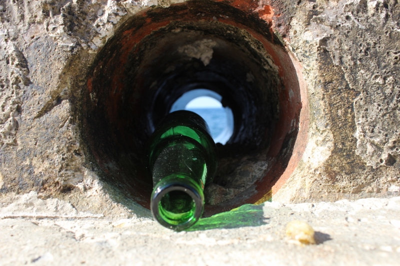 Photo of a bottle resting in a circular-shaped hole in a rock formation.